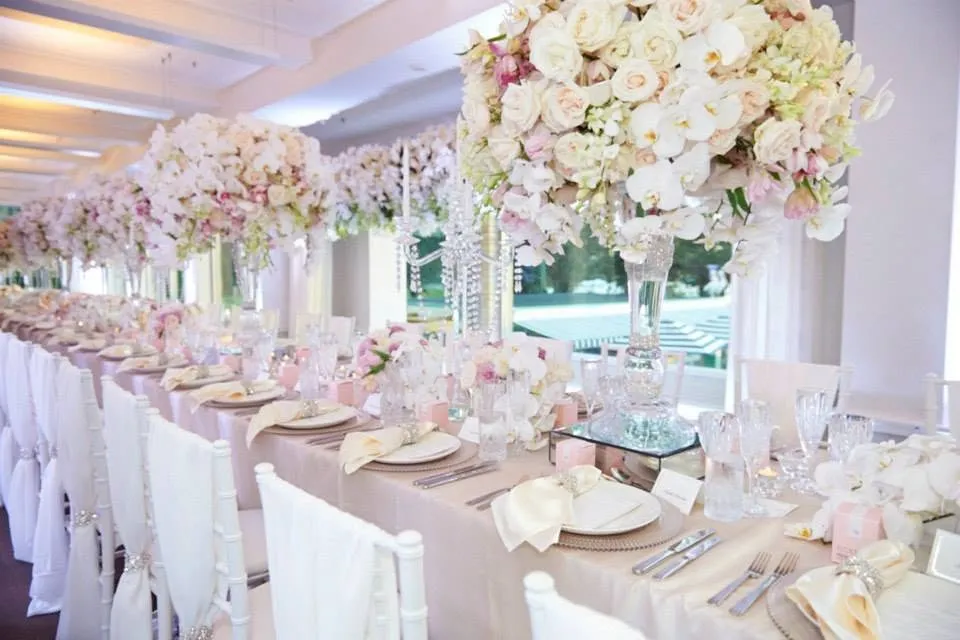A long wedding table lined with tall floral arrangements