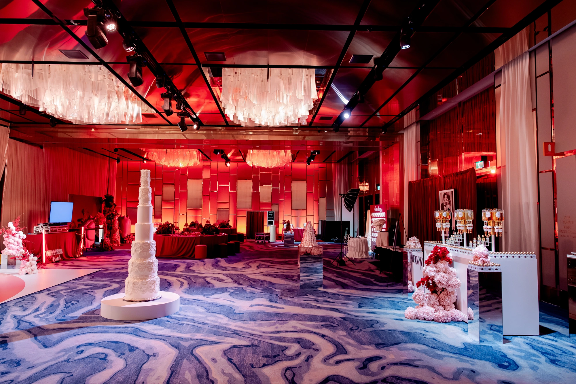 A styled exhibitor floor with a tiered wedding cake and floral installations at Wedded World